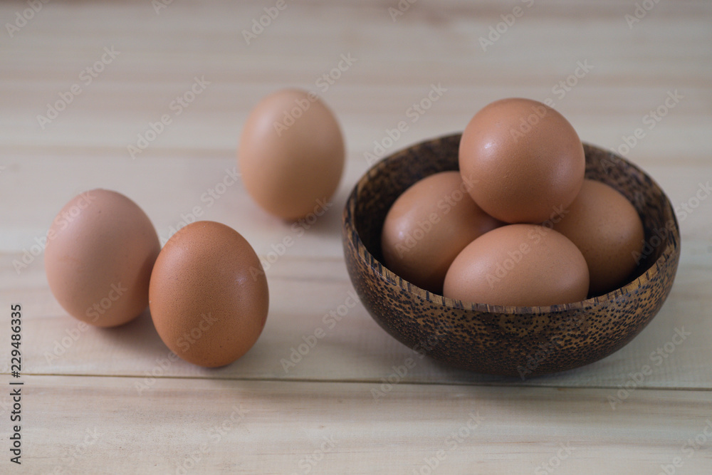 Fresh poultry egg inside bowl on wooded table by the window with copy space. Lit by natural light. Fresh poultry egg inside bowl on wooded table by the window with copy space. Lit by natural light.