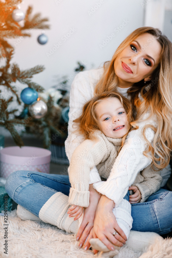 mother and daughter sitting by the christmas tree mother and daughter sitting by the christmas tree