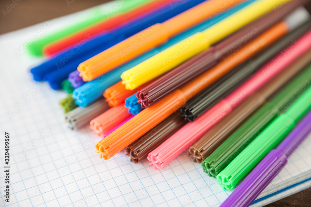 Multicolored felt pens with notebook on wooden background. Recreation concept drawing Multicolored felt pens with notebook on wooden background. Recreation concept drawing