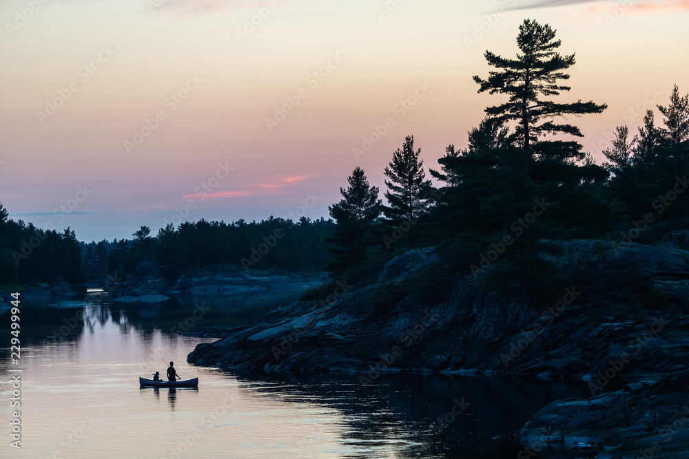 Silhouette of father and son fishing in a canoe in the Canadian wilderness