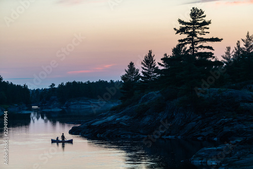 Obraz na płótnie Silhouette of father and son fishing in a canoe in the Canadian wilderness w salonie