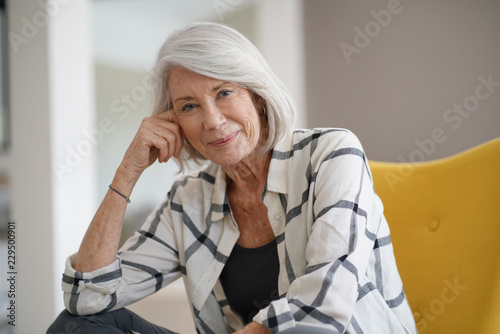   Stylish senior woman sitting casually indoors and smiling