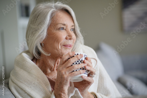  Cosy looking senior woman at home with hot drink photo
