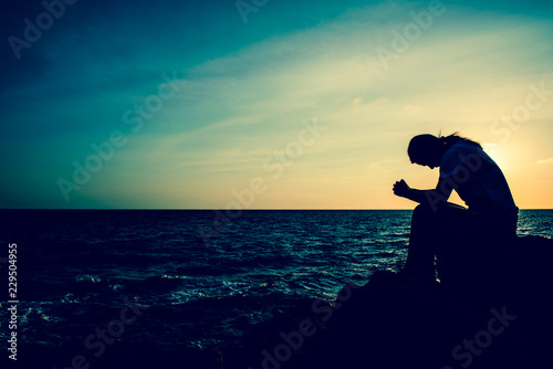 Tela Silhouette women sitting alone on the rock
