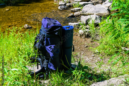 Touristic backpack on a bank of river in forest