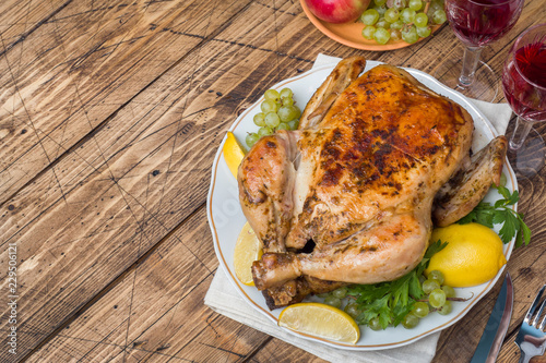 Baked chicken, wine glasses and fruit for dinner on the festive table. copy space