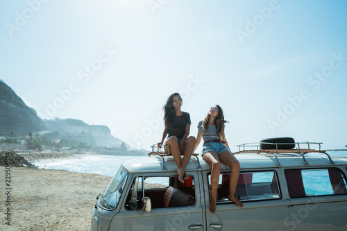 Hipster girl relaxing on the retro van roof in her summer road t © Odua Images