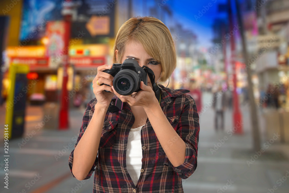 Tourist girl taking photograph from walking street in Chinese night market.