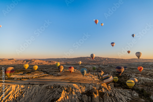 Aerial view of numerous hot air balloons flying all over the unique geological features of Cappadocia during the sunrise, Turkey © anahtiris