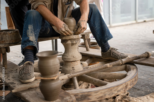 Potter hands makes on the pottery wheel clay pot	 photo