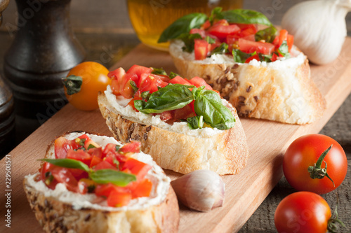 Italian tomato and cheese bruschetta. Tapas, antipasti with chopped vegetables, herbs and oil on grilled ciabatta and baguette bread.