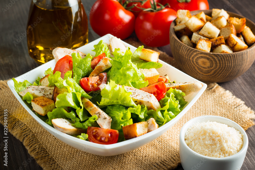 Fresh salad with delicious chicken breast, ruccola, spinach, cabbage, arugula and tomato on wooden background. Oil, salt and pepper. Fresh salad with delicious chicken breast, ruccola, spinach, cabbage, arugula and tomato on wooden background. Oil, salt and pepper.