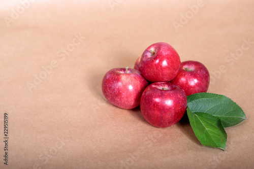 Red apples with green foliage lie on a light background. Space for text.