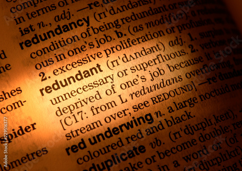 CLOSE UP OF DICTIONARY PAGE SHOWING DEFINITION OF THE WORD REDUNDANT