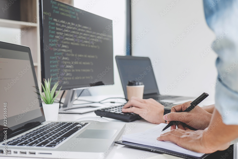 Writing codes and typing data code technology, Programmer cooperating working on web site project in a software developing on desktop computer at company Writing codes and typing data code technology, Programmer cooperating working on web site project in a software developing on desktop computer at company