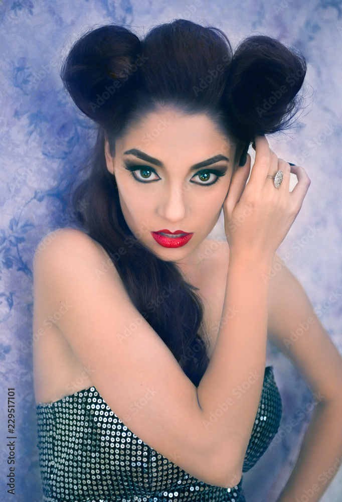 Fototapeta premium Sexy Caucasian model looking like a vampire with her black stiletto nails in the hair, sculpting make-up and cocktail dress with big cleveage. Maleficent lookalike and Halloween concept