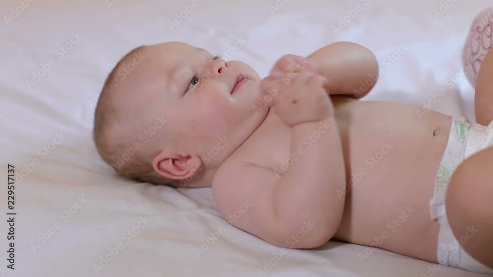Portrait of a cute newborn baby in white clothes on the bed in the bedroom, he moves his arms and legs. Portrait of a cute newborn baby in white clothes on the bed in the bedroom, he moves his arms and legs.