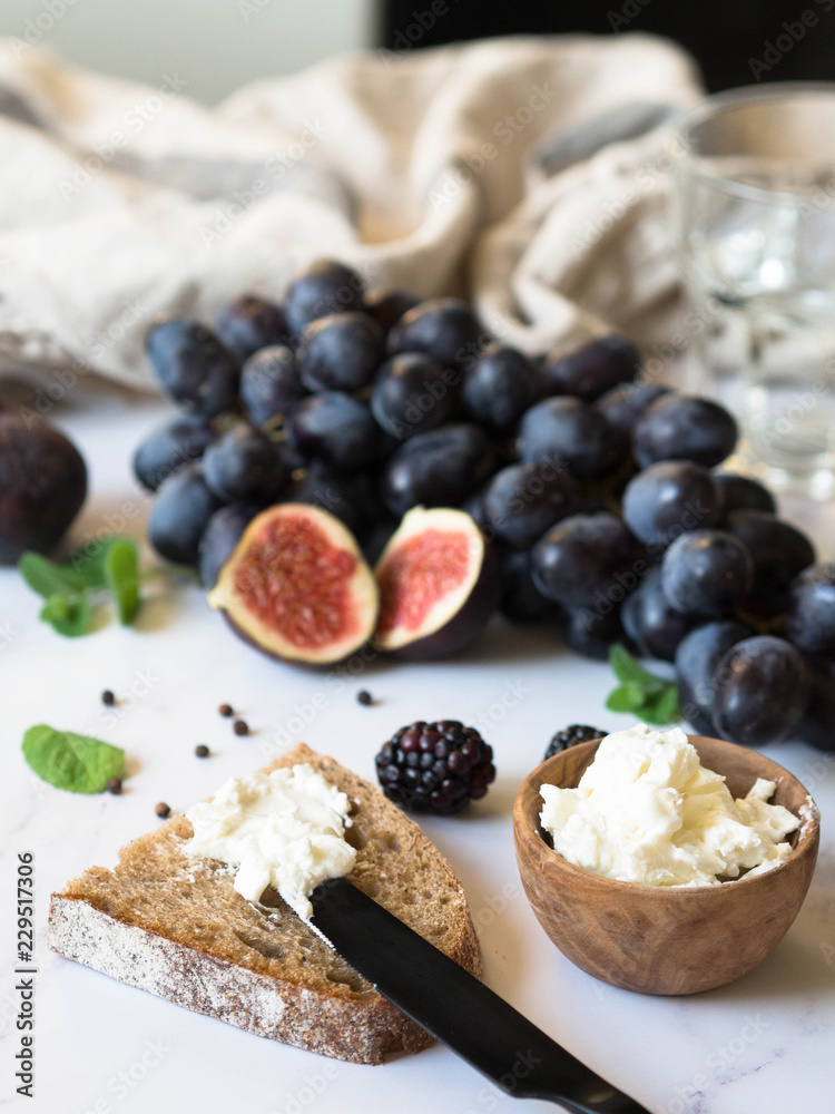 Rye bread and a knife with cream cheese and various fruits on a marble background. Cooking toast with cheese and berries. Rye bread and a knife with cream cheese and various fruits on a marble background. Cooking toast with cheese and berries.