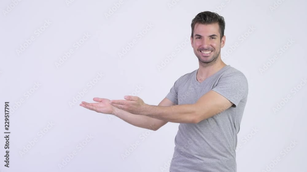 Young happy Hispanic man showing something Young happy Hispanic man showing something