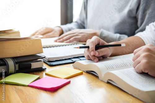 High school tutor or college student group sitting at desk in library studying and reading, doing homework and lesson practice preparing exam to entrance, education, teaching, learning concept