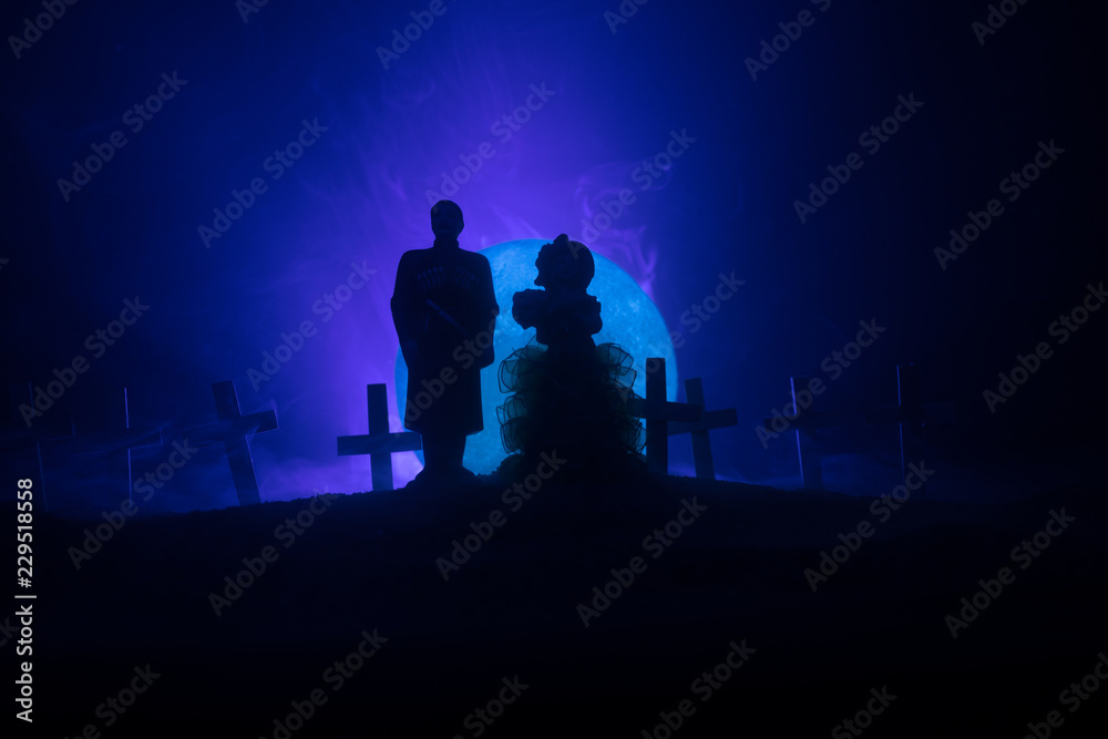 Fototapeta premium Halloween. Scary zombie bride on a night cemetery holds a pumpkin lantern.