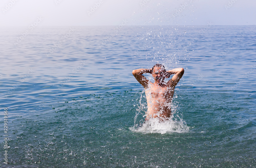 Man splashing water into the sea during summer holidays