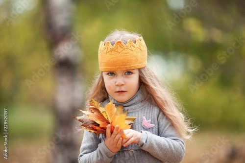 beautiful girl in knitted crown walks in autumn park