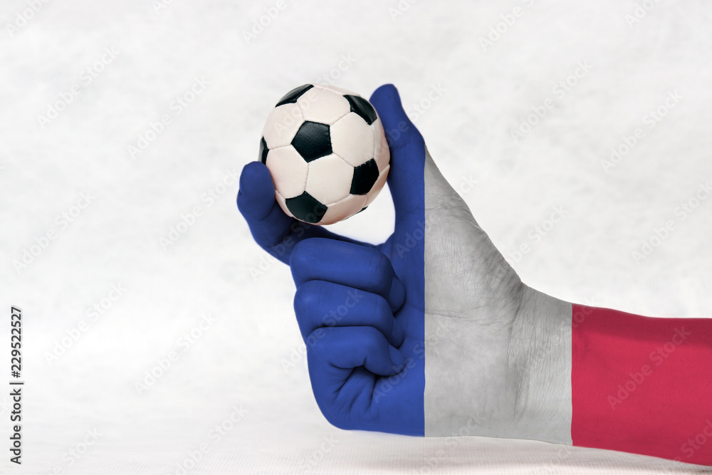 Mini ball of football in France flag painted hand on white background. Concept of sport or the game in handle.