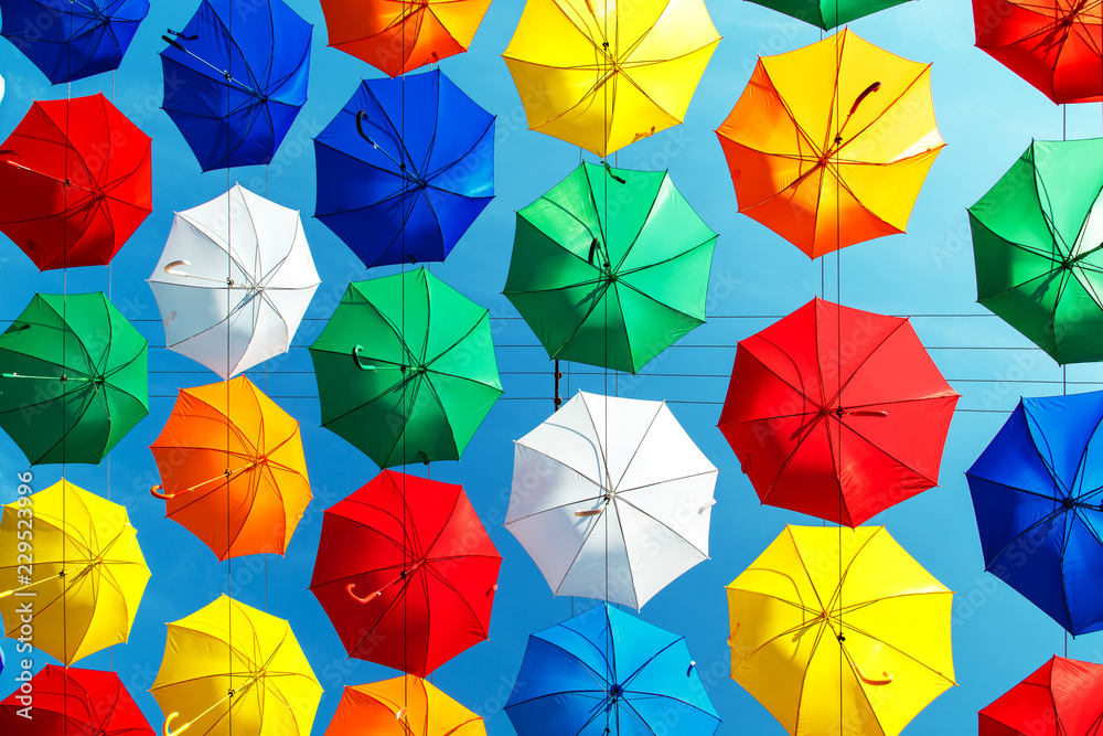 Naklejka premium Multicolored floating umbrellas against the blue sky.