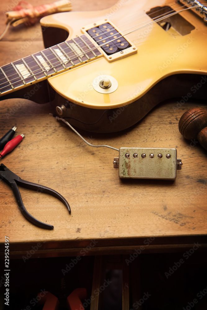 Electric guitar repair. Vintage electric guitar on a guitar repair shop work bench. gold color