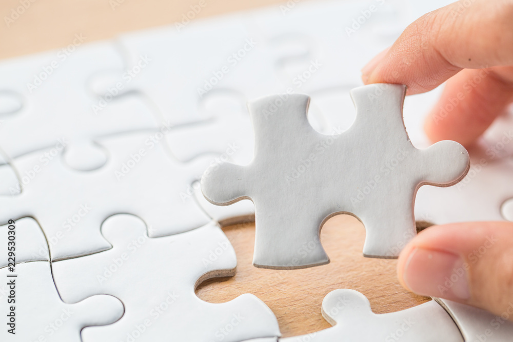Fototapeta premium Hand put the last piece of jigsaw puzzle to complete the mission.