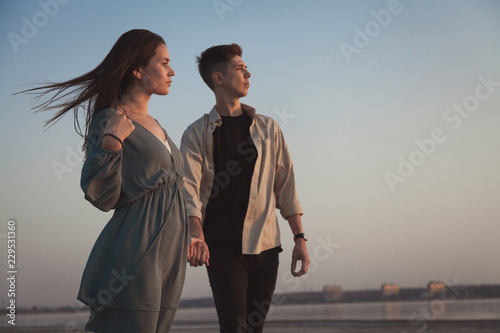 Beautiful loving young couple on the background of blue sky look one way.