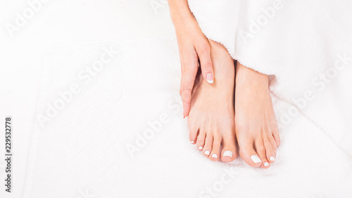 Female feet on towel. Nails getting a fresh and accurate look during a pedicure procedure