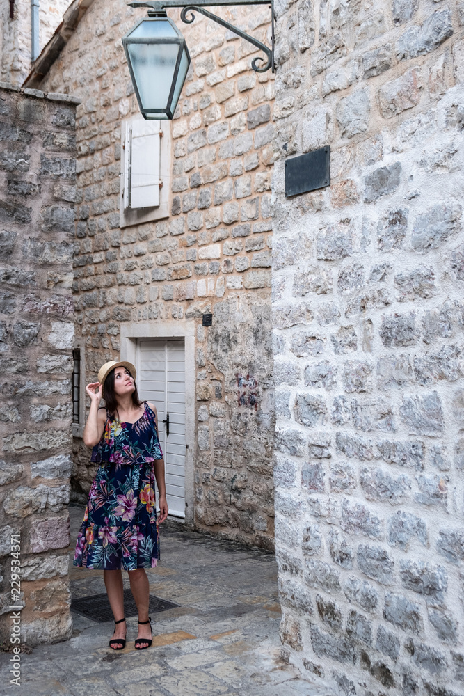 Europe summer travel mediterranean destination. Tourist woman on vacation, walking on the streets of old and beautiful Mediterranean city in hat and summer dress