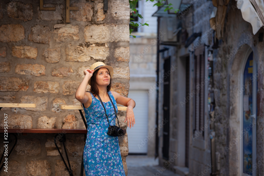 Young attractive cheerful travel girl walking with camera in old Mediterranean city. Summer travel concept