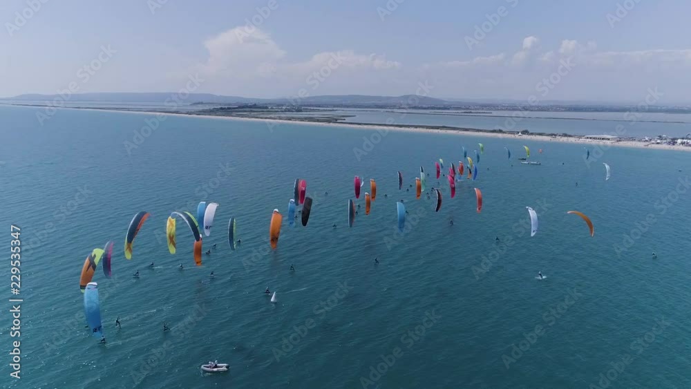 big group of kitesurfers racing, view by drone. Sunny day coastline 