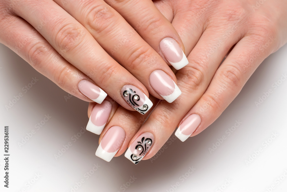 classic white French manicure with black monograms and crystals on long square nails on a white background close-up
classic white French manicure with black monograms and crystals on long square nails on a white background close-up