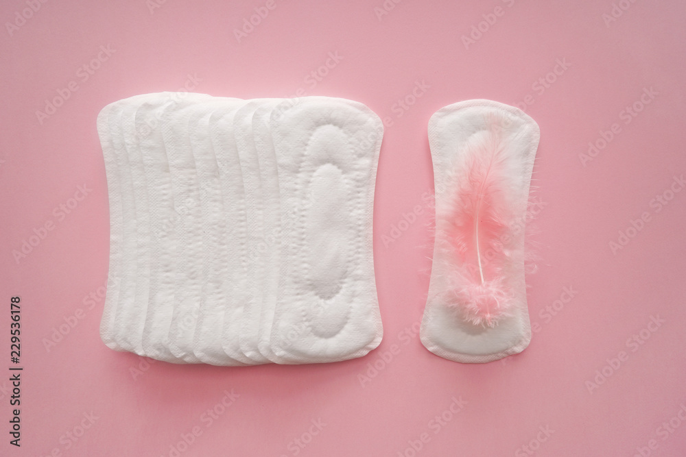 Menstrual pads with feather on color background Menstrual pads with feather on color background