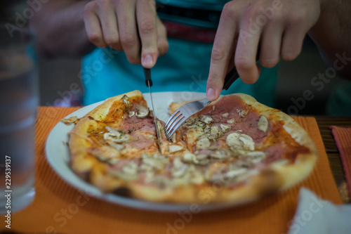 Close Up on hands slicing pizza in a plate