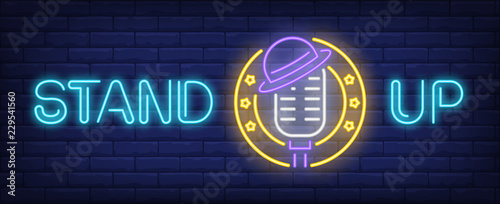 Stand up neon text with microphone and hat. Show invitation advertisement design. Night bright neon sign, colorful billboard, light banner. Vector illustration in neon style.