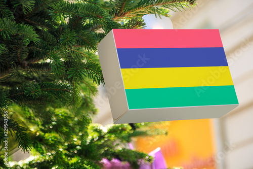 Mauritius flag printed on a Christmas gift box. Printed present box decorations on a Xmas tree branch on a street.