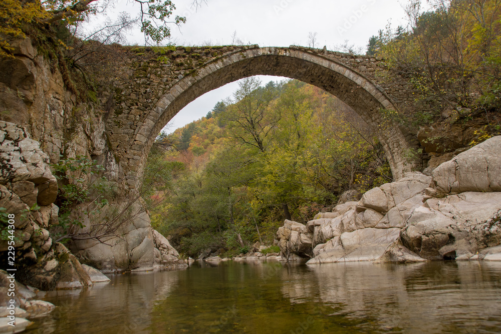 Traditional old stone bridge on river in Greece