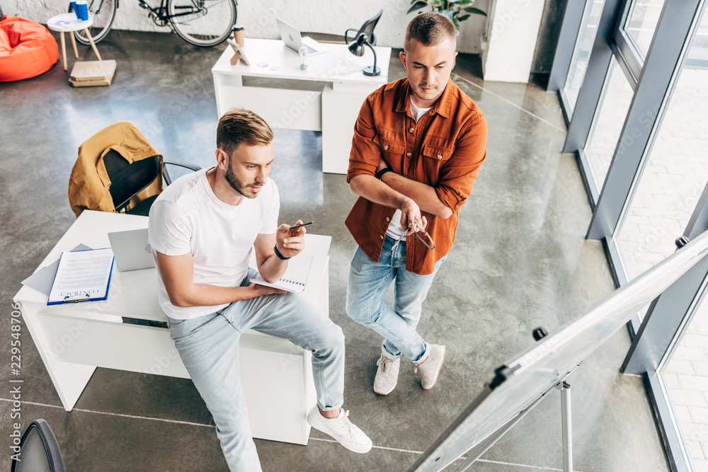 © LIGHTFIELD STUDIOS - high angle view of young entrepreneurs looking at whiteboard at office © LIGHTFIELD STUDIOS - high angle view of young entrepreneurs looking at whiteboard at office