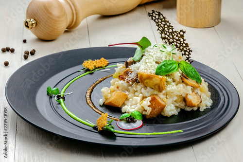 Classic Italian risotto cooked in a vegetable broth with porcini mushrooms and parmesan on a wooden table. Delicious vegetarian Italian cuisine rice meal.