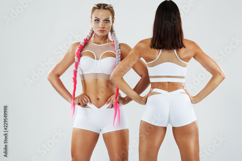 Two fitness athletics women in sportswear isolated on white background. Sport and fashion concept with copy space.