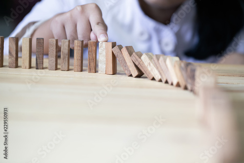 Images of hand stopping domino effect with his finger. Business crisis concept.