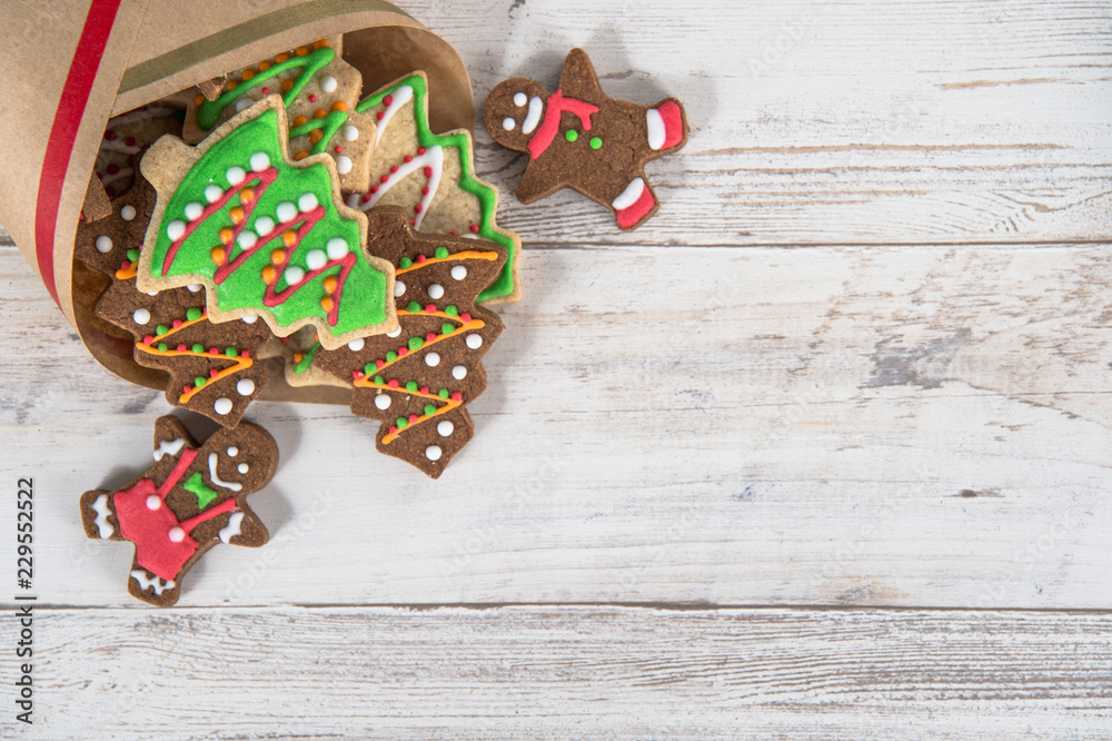 Beautiful Christmas composition and decoration with baked Christmas gingerbread cookies in paper bag on light wooden background, flat lay, top view, copy space (text space)