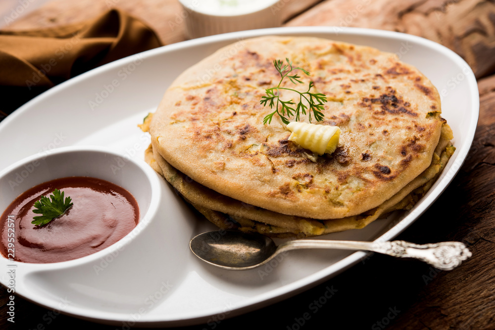 Aloo Paratha / Indian Potato stuffed Flatbread. Served with fresh curd and tomato ketchup. selective focus Aloo Paratha / Indian Potato stuffed Flatbread. Served with fresh curd and tomato ketchup. selective focus