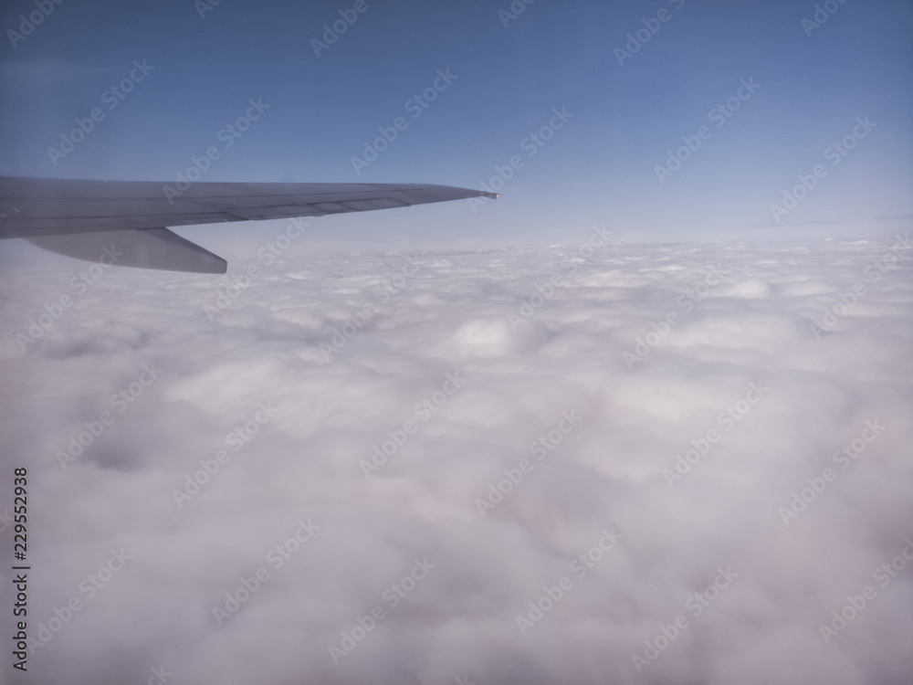 Obraz premium A plane's wing, cotton clouds, immensity feeling