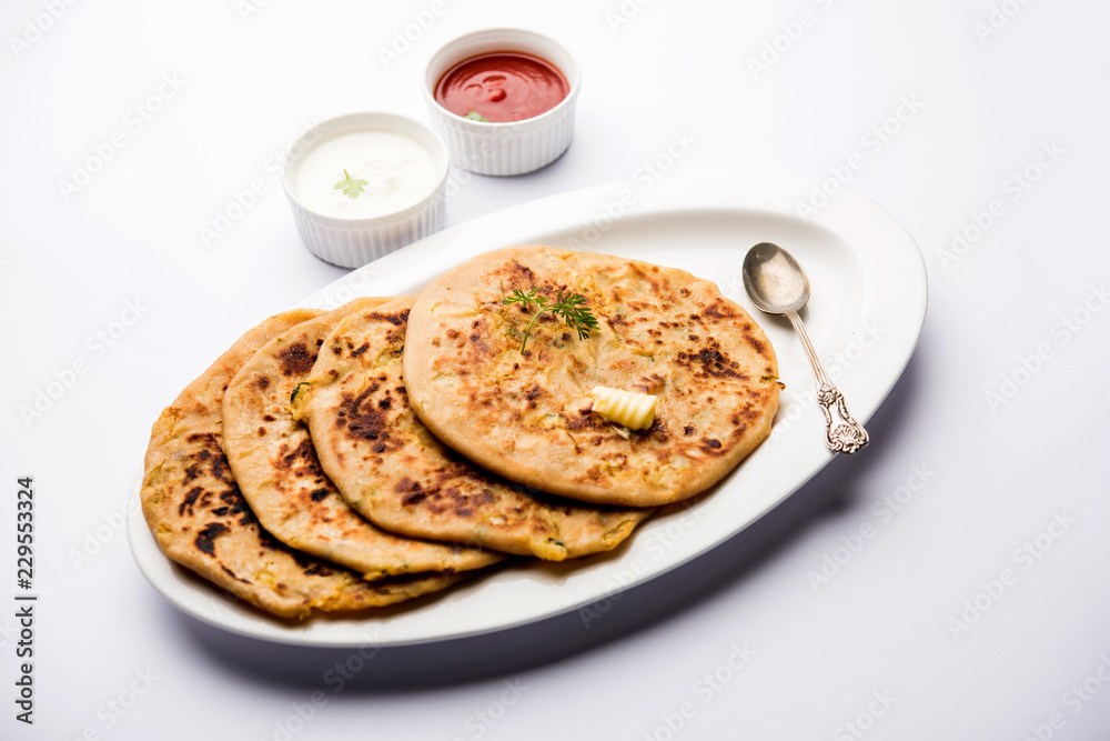 Aloo Paratha / Indian Potato stuffed Flatbread. Served with fresh curd and tomato ketchup. selective focus Aloo Paratha / Indian Potato stuffed Flatbread. Served with fresh curd and tomato ketchup. selective focus